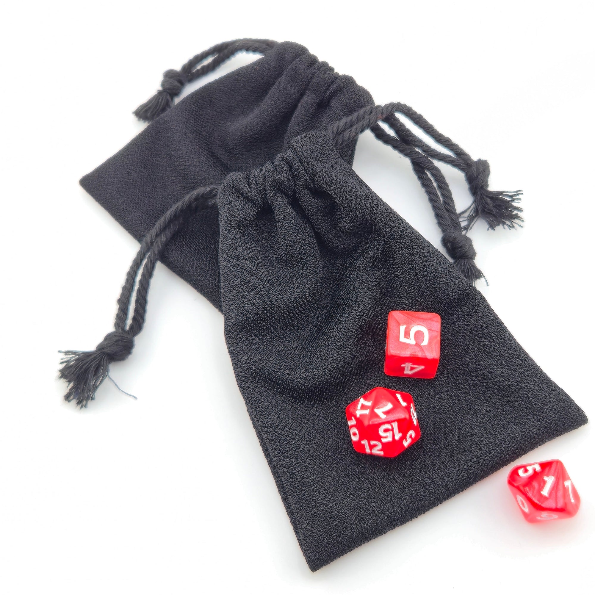 Matte black drawstring bag on a white background with red dice typically used in a traditional dungeons and dragons set up.